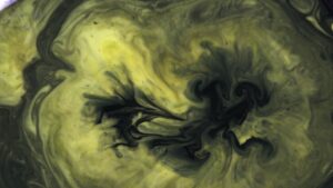 Top view of colorful paints mixed in water. Beautiful yellow and black ink stains background.